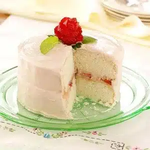 Deliciously moist white cake decorated with flowers and berries on a table.